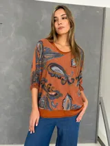 Blusa de algodón con diseño de doble capa, compuesta por una musculosa base y una capa superior de tejido liviano con estampado paisley en tonos naranja, celeste y marrón. Presenta un corte oversize y mangas tres cuartos.