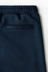 Short azul marino de punto con leve brillo, cintura elástica con cordón de ajuste y ribetes laterales en color blanco.
