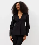 Blazer sastre Blue Steel de color negro, confeccionado en poliéster con elastano y forro de poliéster. Presenta un diseño estructurado con escote en V pronunciado, cierre frontal de un botón y bolsillos con solapa en los laterales. Las mangas largas tienen volumen tipo cocoon.