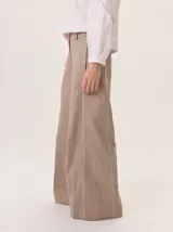 Pantalón de pierna ancha color beige, con pespuntes a contratono y una tira vertical contrastante en el lateral que estiliza la figura.