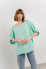 Blusa de lino color verde oliva, de corte amplio y relajado, con escote redondo y mangas 3/4 remangadas.