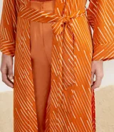 Kimono largo color naranja con estampado de rayas blancas diagonales, mangas largas y lazo para atar en la cintura.