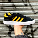 Championes de skate adidas Busenitz Vulc II, color negro con las tres tiras laterales y detalle en el talón en color amarillo. Presentan suela de goma blanca vulcanizada y diseño de perfil bajo.