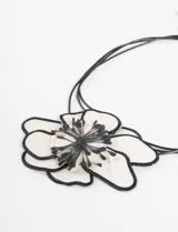 Gargantilla con cordones finos negros y dije de flor de tela blanca con contorno y centro bordados en negro.