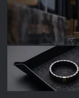 Pulsera elástica compuesta por eslabones de cerámica negra con acabado facetado y una pieza central rectangular con baño de oro.