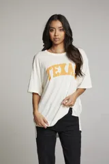 Remera color crema de corte holgado con estampado de la palabra "TEXAS" en color naranja.