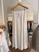 Pantalón palazzo Ciara de tiro alto color blanco, con pinzas delanteras, cintura elastizada y lazo ajustable del mismo género.