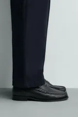 Mocasín de vestir para hombre confeccionado en piel con acabado abatanado, de color marrón. Cuenta con detalle de antifaz en el empeine, horma redonda, plantilla interior de piel y suela a contraste con ligero tacón.