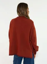 Sweater de tejido de punto en color azul marino, con cuello redondo, mangas largas con puños acanalados y ajuste holgado. Presenta un pequeño aplique decorativo en el ruedo.