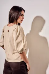 Remera de algodón negro con mangas cortas abullonadas, cuello redondo y costura central frontal.