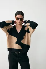 Sweater de punto con diseño animal print en bloques de color negro y beige, con cuello en V y terminaciones acanaladas en puños y ruedo.