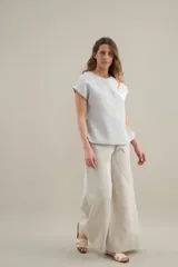 Blusa de silueta amplia y relajada, confeccionada en lino con cuello redondo, mangas cortas y recorte diagonal en el frente.