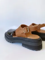 Sandalias de cuero color negro y camel, con plataforma track y hebilla ajustable.