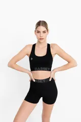 Top deportivo negro con logo blanco en el frente y banda elástica con letras grises en el bajo busto.