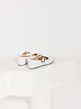 Ballerinas blancas de cuero charol con hebilla dorada y suela negra.