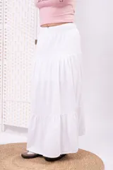 Pollera larga blanca de tiro alto, con cintura elástica y diseño amplio de volados escalonados.