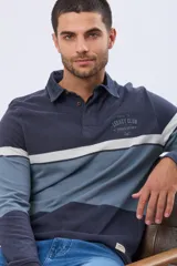 Remera polo de manga larga con diseño de bloques de color horizontales en tonos azul, verde y marrón. Presenta cuello clásico, cierre frontal con botones y bordado en el pecho. Cuenta con puños elásticos acanalados.