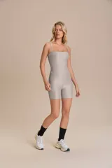 Jumpsuit corto de diseño ajustado con escote cuadrado y breteles finos. Confeccionado en tejido técnico con acabado ligeramente brillante y textura acanalada, ofrece compresión media y alta elasticidad.
