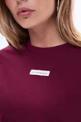 Remera de manga larga en color blanco, con cuello redondo y corte clásico. Presenta una pequeña etiqueta decorativa en el centro del pecho.