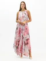 Vestido largo de fiesta con estampado floral en tonos rosa y gris sobre fondo blanco. Presenta cuello halter con abertura tipo lágrima, cintura drapeada y falda amplia con capas asimétricas y bajo en picos. Confeccionado en tejido ligero con forro interior.
