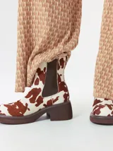 Bota tipo chelsea de cuero vacuno en color rojo con estampado floral grabado en negro. Presenta paneles laterales elásticos, suela de plataforma y taco cuadrado en color negro.