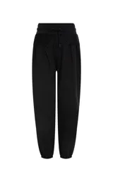 Pantalon tipo jogger de tiro alto, color negro, confeccionado en tejido de punto. Presenta una cinturilla elástica ancha con cordón ajustable y detalle de superposición de encaje en la parte delantera. Cuenta con bolsillos laterales ribeteados, perneras ligeramente holgadas y puños ajustados con elástico.