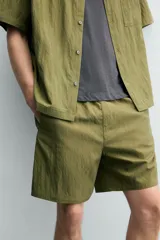 Bermuda relaxed fit de color azul marino confeccionada en tejido fluido con mezcla de viscosa, cintura elástica con cordón interior y bolsillos frontales.