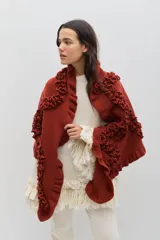 Chal de lana color marrón con diseño envolvente, decorado con volados aplicados en toda la superficie que aportan textura y movimiento.