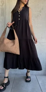 Vestido midi negro con escote en V, sin mangas, corte holgado y tres botones en la parte superior.