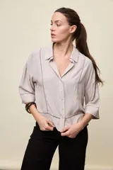 Camisa de calce relajado color celeste, con mangas 3/4, cuello clásico y cierre frontal con botones. Presenta detalles calados en el frente y en las mangas que aportan un acabado delicado al diseño.