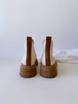 Botas Chelsea de cuero color crudo con elástico lateral, suela track color caramelo y tirador trasero de cuero con textura croco color marrón.