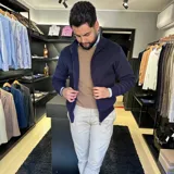 Campera tejida color marrón claro con cierre frontal, cuello alto y mangas largas con puños acanalados.