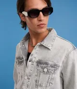 Campera de jean de hombre, color celeste claro con efecto desteñido y desgastado. Presenta cuello, manga larga, cierre frontal con botones blancos y dos bolsillos con solapa y botón en el pecho.