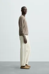 Jersey color crudo de tejido de punto, con cuello redondo y mangas largas. Corte amplio y terminaciones en rib.