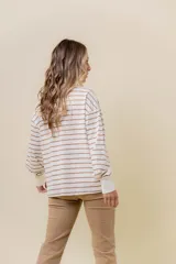Buzo liviano de manga larga con diseño de rayas horizontales en color beige y blanco. Presenta un cuello redondo con cartera frontal de botones tipo henley, hombros caídos y calce holgado con puños acanalados.