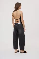 Jean de tiro medio y corte barrel con pierna amplia y ligeramente curva, estilo de cinco bolsillos en denim negro lavado.