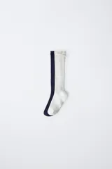Pack de dos pares de calcetines altos de tejido acanalado, uno en color azul marino y otro en color blanco, ambos con un pequeño aplique de lazo decorativo en la parte superior.