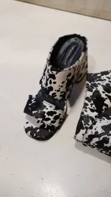 Sandalias de tacón alto y ancho, confeccionadas en piel con acabado de pelo y estampado animal print de vaca en tonos marrones y blancos, con tiras anchas en el empeine.