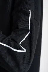 Sweater negro de calce oversize, confeccionado en algodón peinado con textura sutil. Presenta cuello redondo y una línea vertical blanca decorativa a lo largo de las mangas largas.