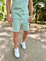 Conjunto deportivo para hombre compuesto por una remera de manga corta con cuello redondo y un short con cordón ajustable en la cintura, ambos en color verde menta.