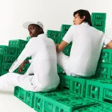 Chomba blanca de piqué de algodón con cuello clásico y tapeta de dos botones. Presenta logo de Lacoste y cocodrilo pixelado de Minecraft bordados en el pecho.