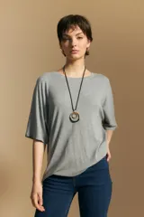 Remera de calce relajado con silueta fluida, confeccionada en tejido de viscosa con elastano. Presenta cuello redondo, mangas cortas y un diseño minimalista de caída suave.