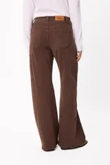 Jean de corte wide leg en color marrón chocolate, con tiro medio y cierre frontal con botón y cremallera. Presenta un diseño de cinco bolsillos y costuras visibles.