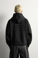 Sudadera negra de corte boxy fit, confeccionada en tejido compacto con elasticidad. Presenta capucha, manga larga, bolsillo frontal tipo canguro y acabados en rib.