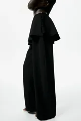 Pantalón negro de corte barrel con pollera mini acampanada superpuesta en la cintura, piernas amplias y cierre lateral.