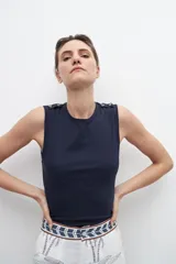 Musculosa verde oliva con cuello redondo y botones decorativos en los hombros.