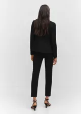 Blazer negro entallado de punto roma con solapas de muesca, hombros estructurados, abertura posterior y dos bolsillos de ribete delanteros.