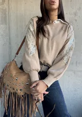 Sweater de punto color beige, con cuello redondo y mangas largas abullonadas. Presenta detalles bordados con lentejuelas y perlas en los hombros y parte superior de las mangas.