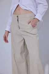 Pantalón de tiro medio y piernas anchas, confeccionado en mezcla de lino y algodón, con bolsillos delanteros y traseros con detalles de costuras pespunteadas a contratono.