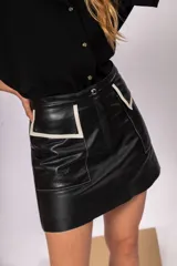 Minifalda negra de cuero con bolsillos frontales y detalles en contraste color hueso.